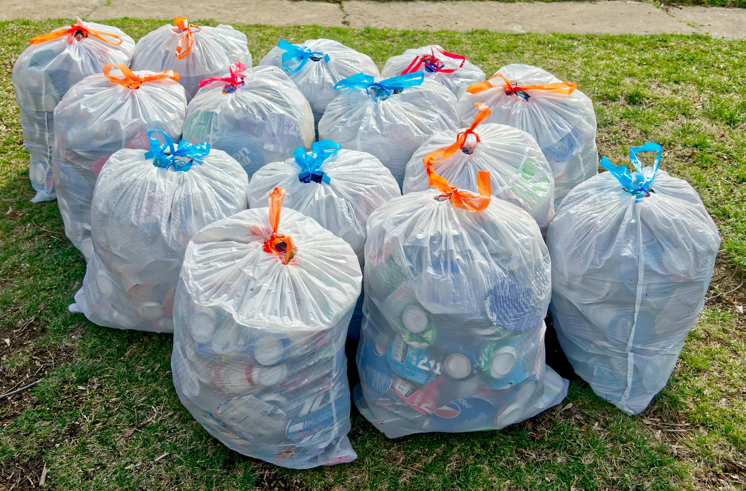 A Bunch of Full Trash Bags Standing on the Grass