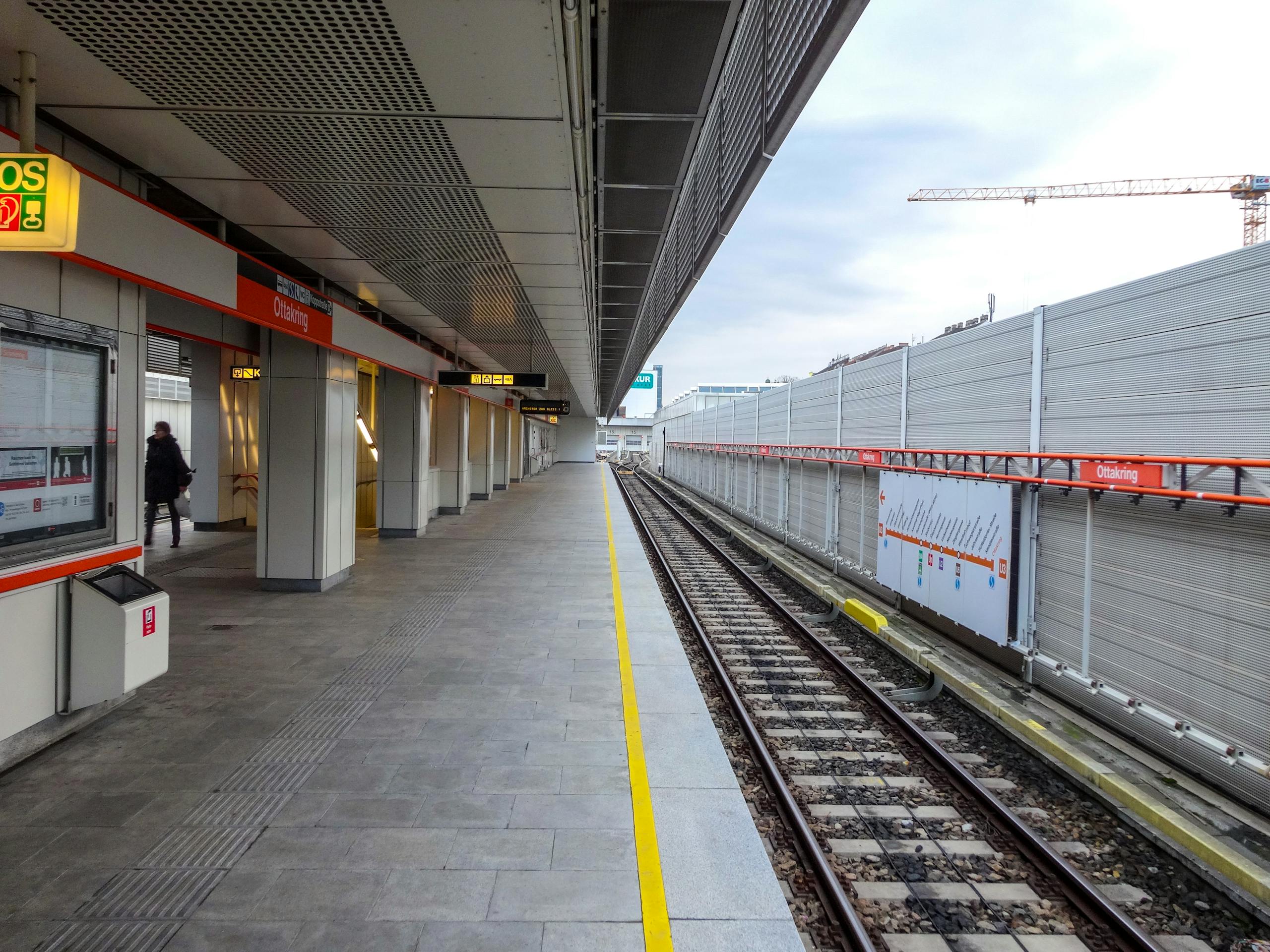 Modern subway platform in Vienna with clear sky backdrop and empty tracks.