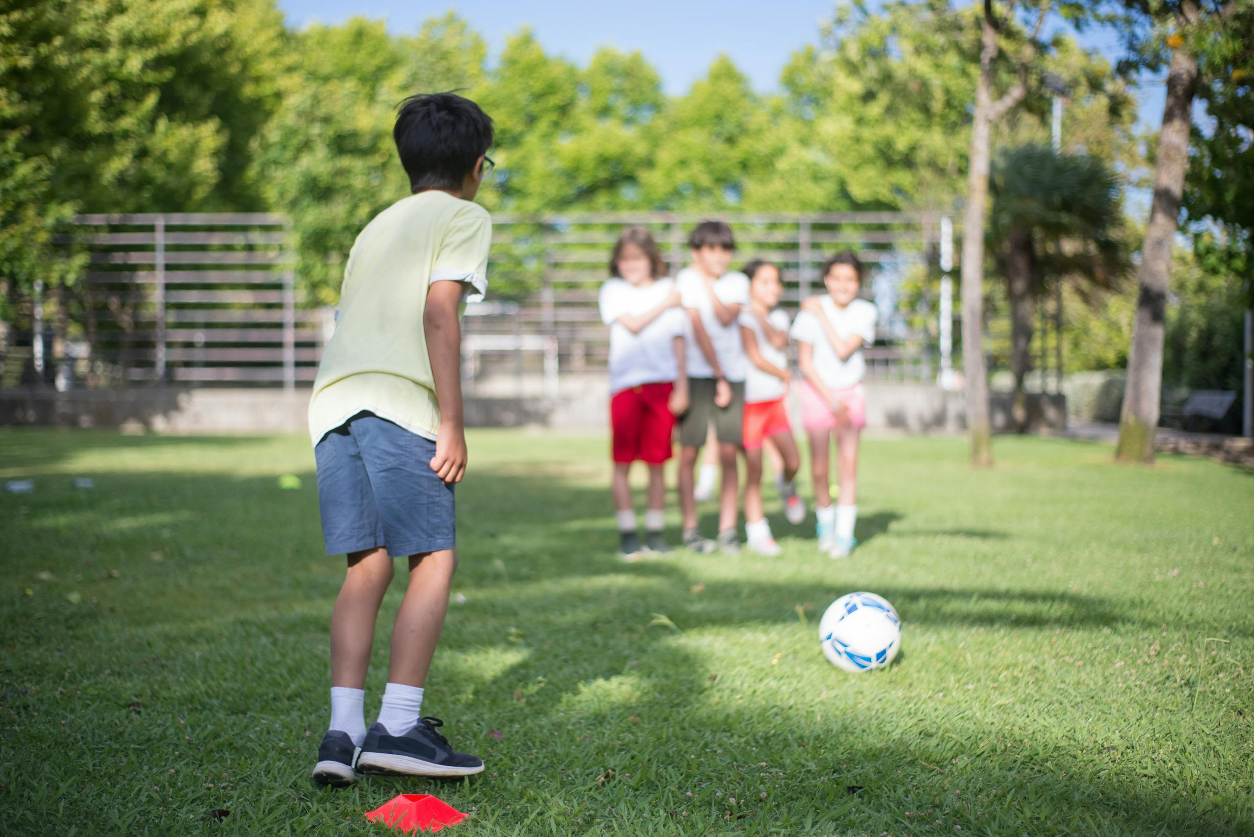Group of children playing soccer in a sunny outdoor park, enjoying a friendly game.