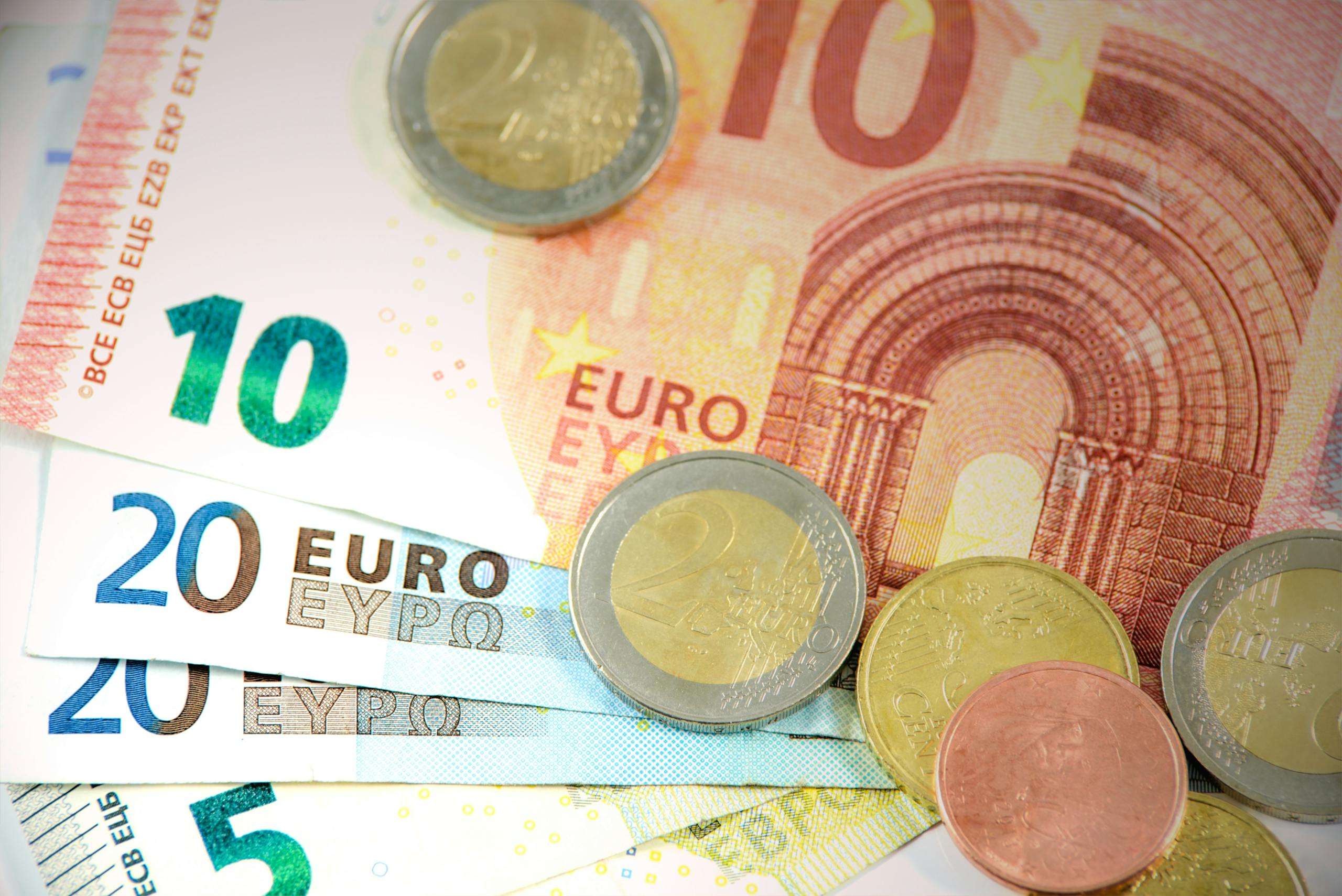 Detailed shot of Euro banknotes and coins showcasing currency denominations.